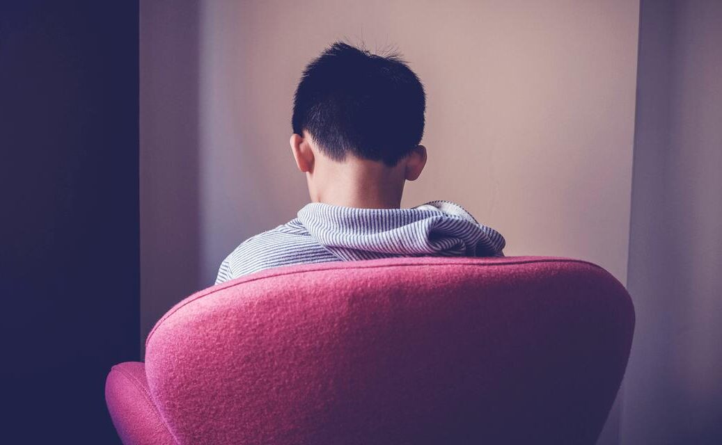 A young person sitting alone, looking away
