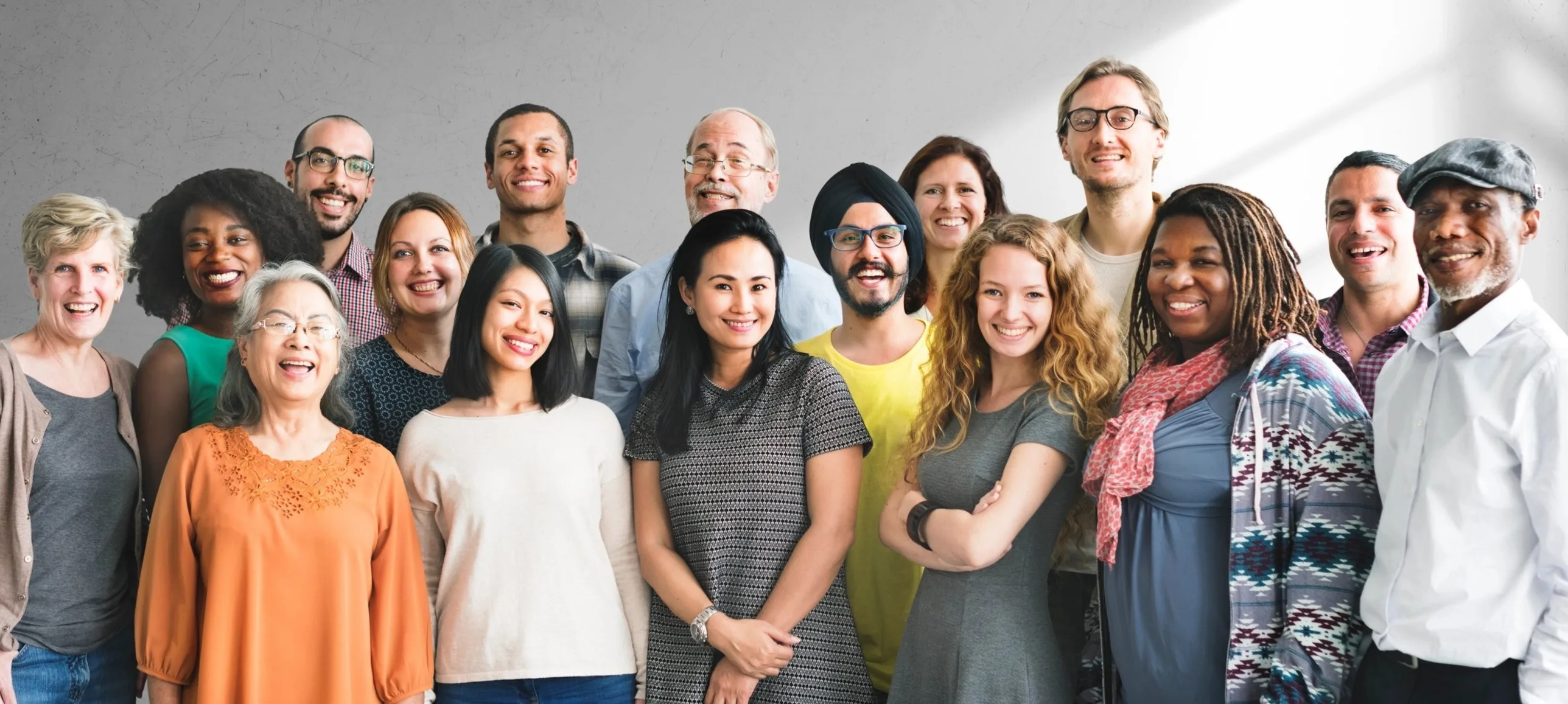 A large group of people of different ages and backgrounds standing together, smiling